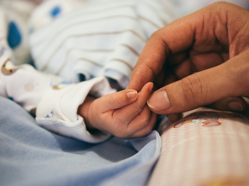 close-up of womens hand touching newborn infant hand - babies and parents